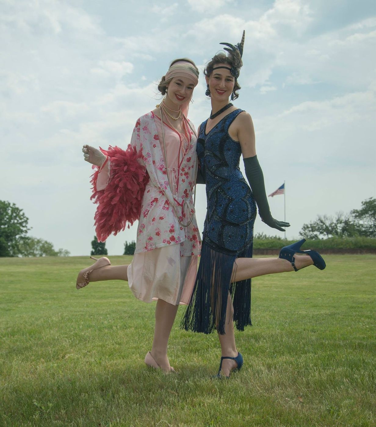 Two models in flapper dresses kicking up heels on a lawn